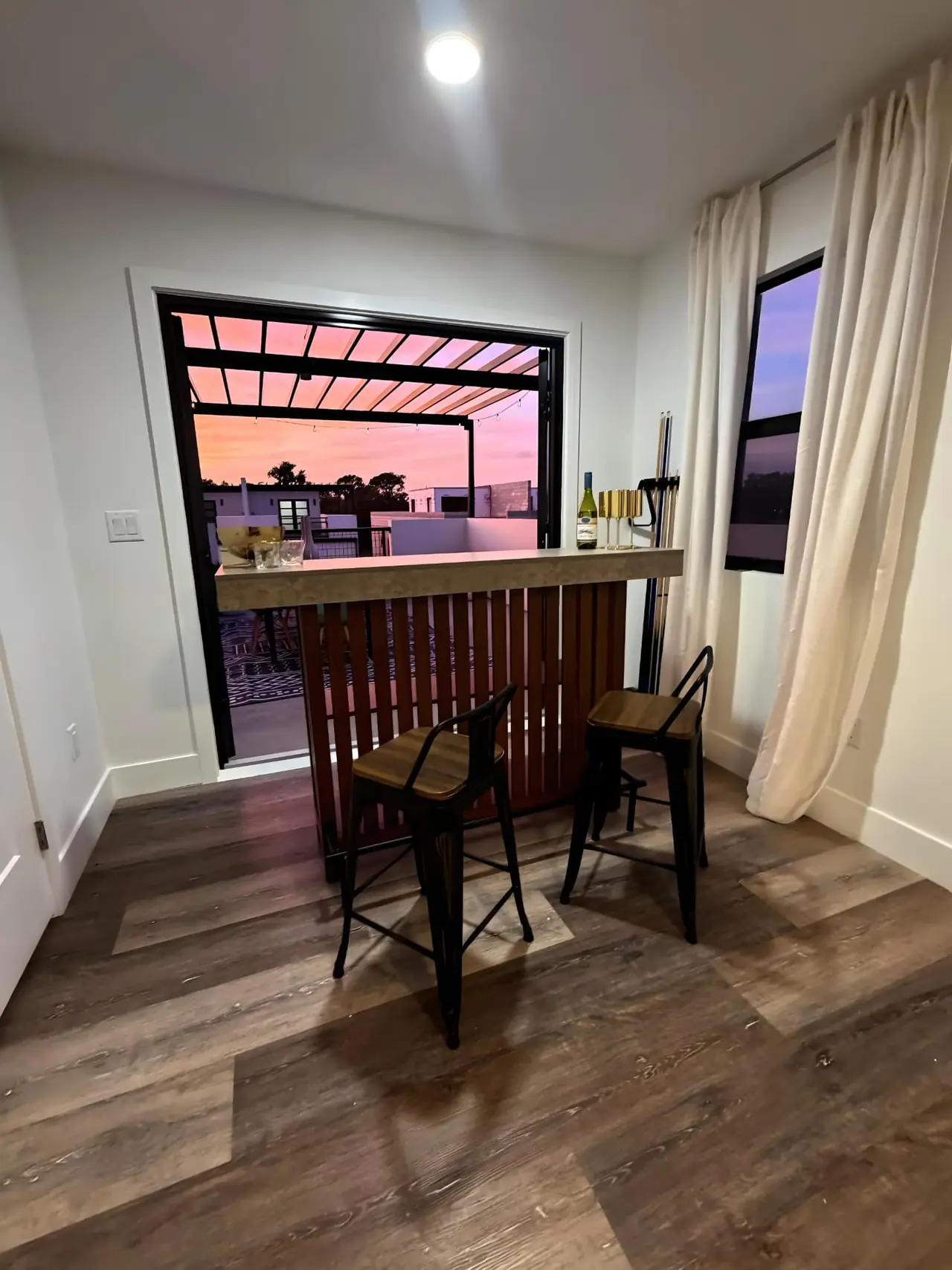 Loft bar looking out through open doors to a rooftop terrace at sunset over Pinellas Park, Florida